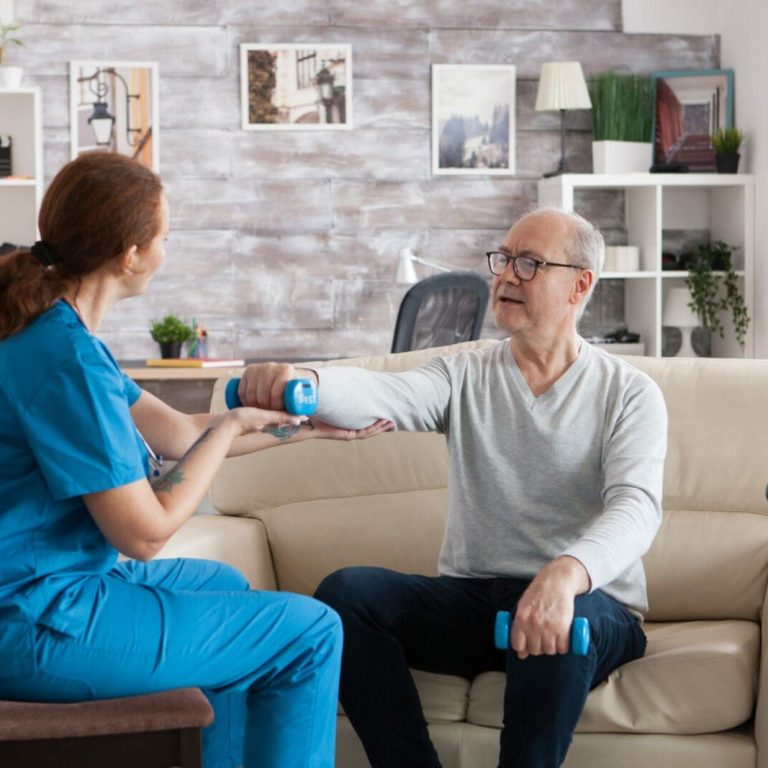 Young nurse doing physiotherapy treatment in nursing home with senior man using dumbbells.